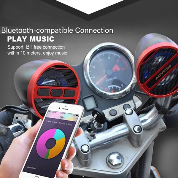 A hand holds a smartphone displaying music controls next to a motorcycle Bluetooth speaker system.