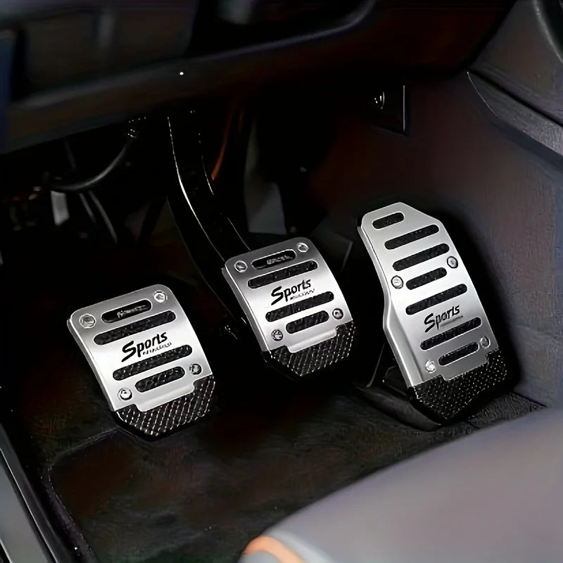 Three silver aluminum sports pedal covers are shown inside a car interior, resting on the floor.