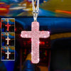 A pink cross pendant made of stainless steel is displayed against a blurred car interior background.