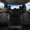 Vista interior de un coche con fundas de cuero negro instaladas, mostrando los asientos delanteros y el tablero.