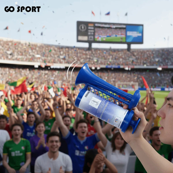A hand holds a blue portable air horn, with a crowd visible in the background.