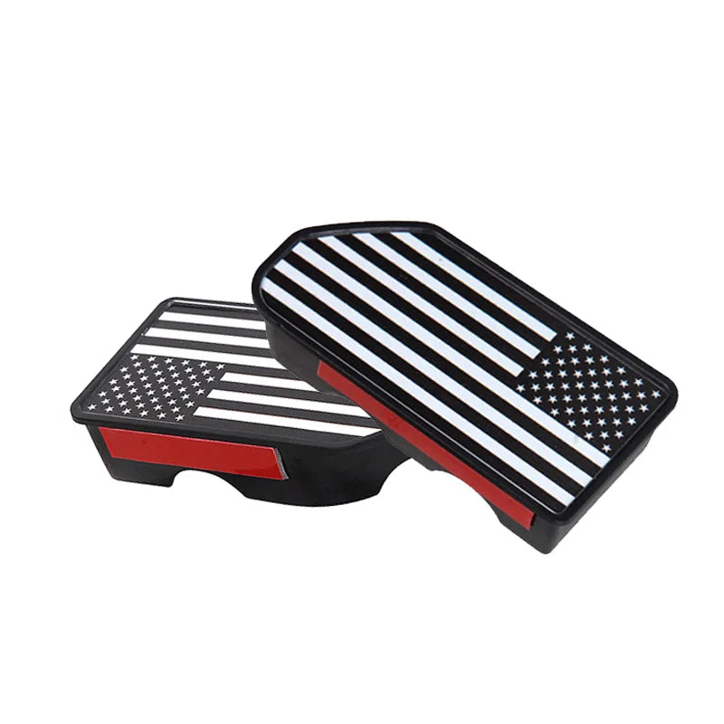 A pair of black and white striped truck bed rail hole plugs featuring an American flag design.