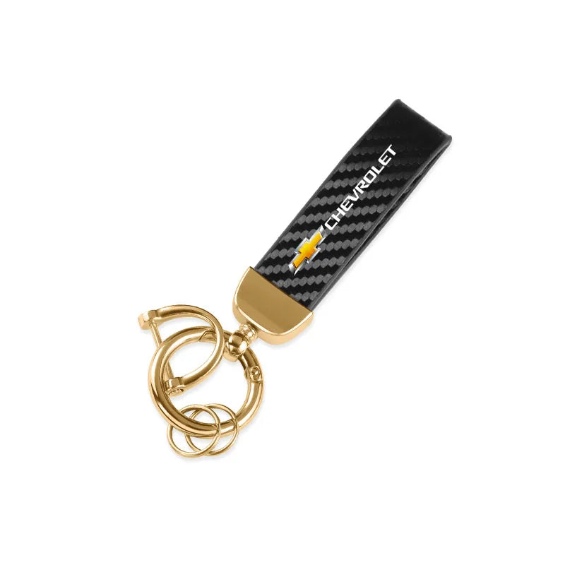 A luxury metal keyring set featuring a black and gold patterned leather strap and a brass split ring.