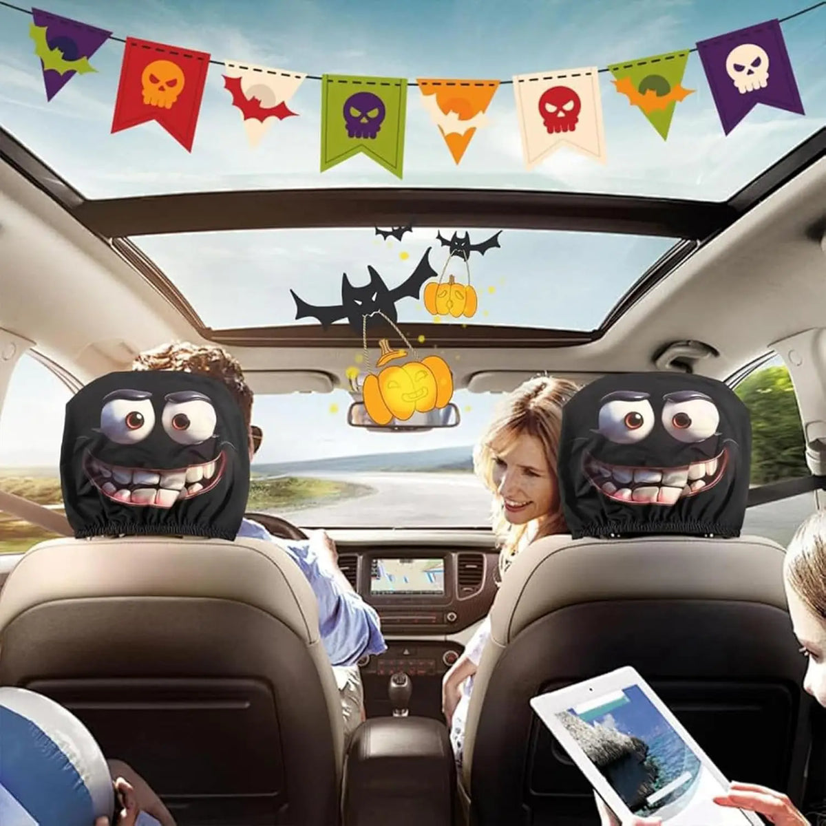 Interior del coche mostrando personas en los asientos delanteros con fundas para la cabeza temáticas de Halloween y pancartas
