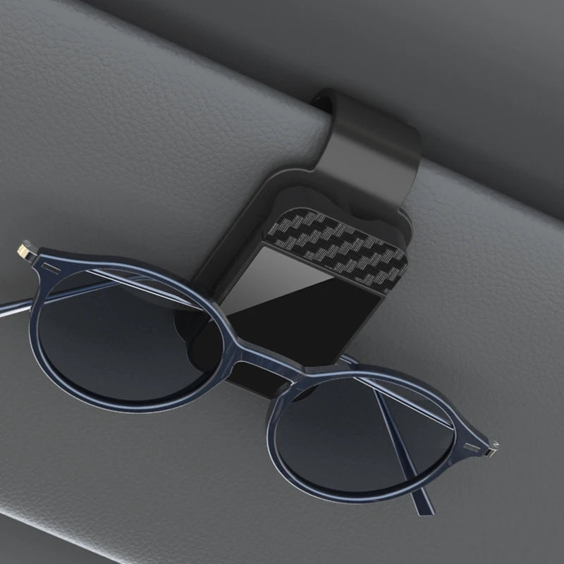 A pair of dark blue sunglasses resting on a black clip holder against a gray background.