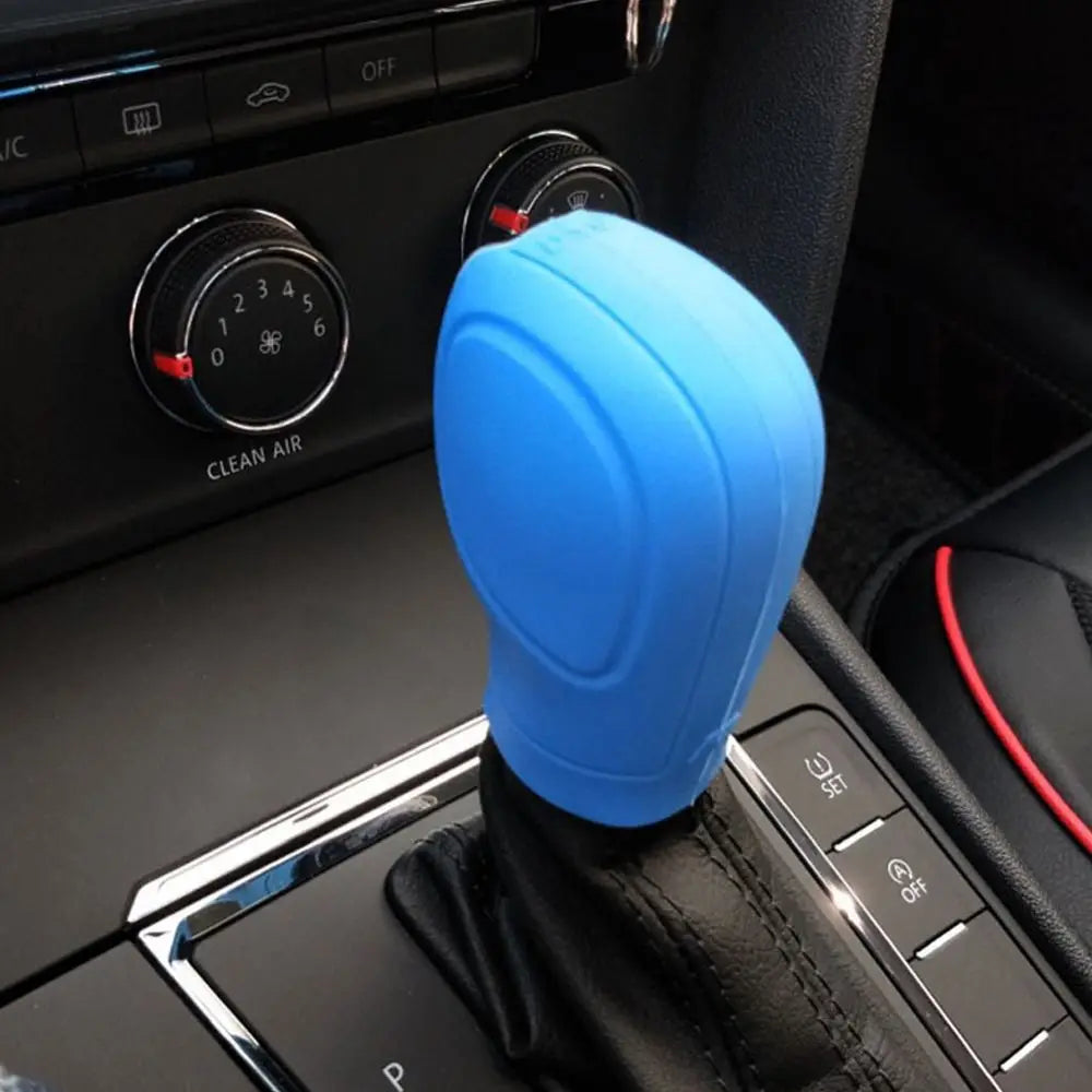 Una tapa de palanca de cambios de silicona azul brillante colocada en la consola interior de un coche cerca de los controles 
