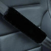 Close-up of a black luxury car seatbelt shoulder pad on a gray car seat interior.