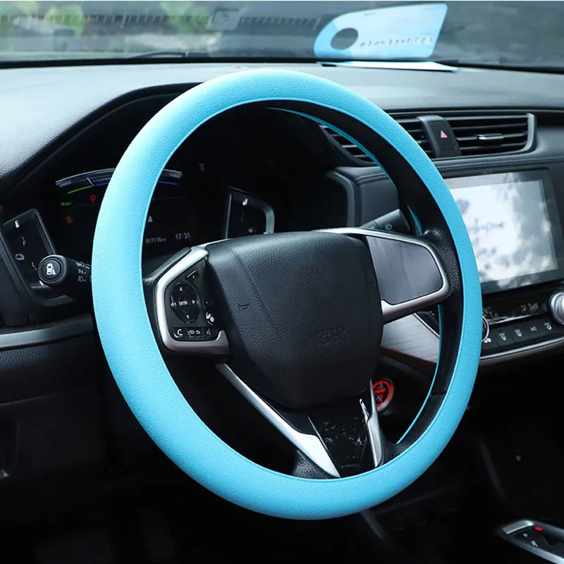 A close-up view of a light blue silicone steering wheel cover installed on a black car steering wheel.