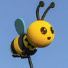A yellow bee antenna decoration with black stripes and a light blue wing against a clear blue sky.