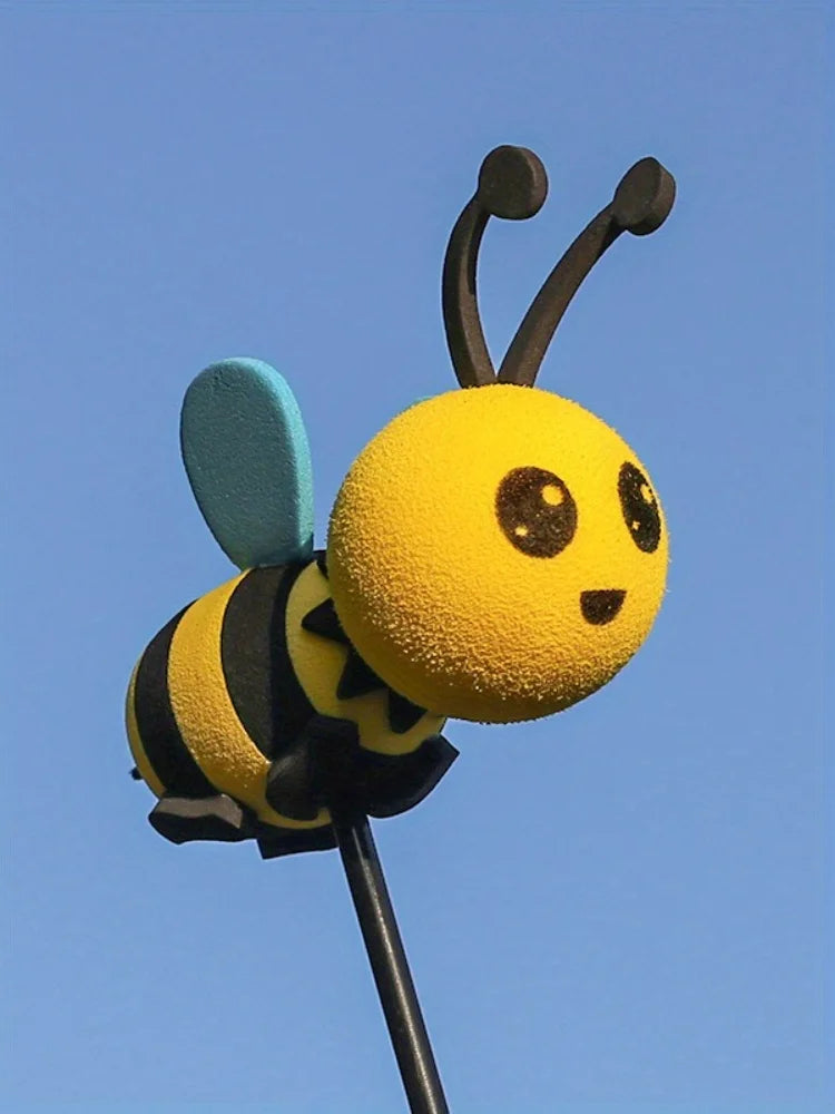 A yellow bee antenna decoration with black stripes and a light blue wing against a clear blue sky.