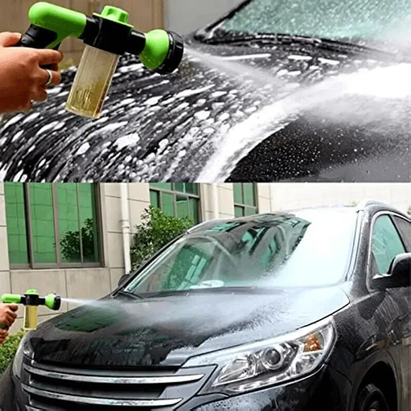 A hand sprays soapy water onto a black car's windshield with a high pressure foam lance for cleaning.