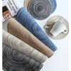 A collection of round and cylindrical placemats made from textured cotton yarn in shades of blue, gray, and beige.