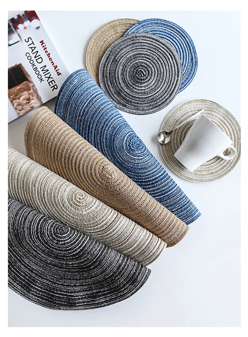 A collection of round and cylindrical placemats made from textured cotton yarn in shades of blue, gray, and beige.