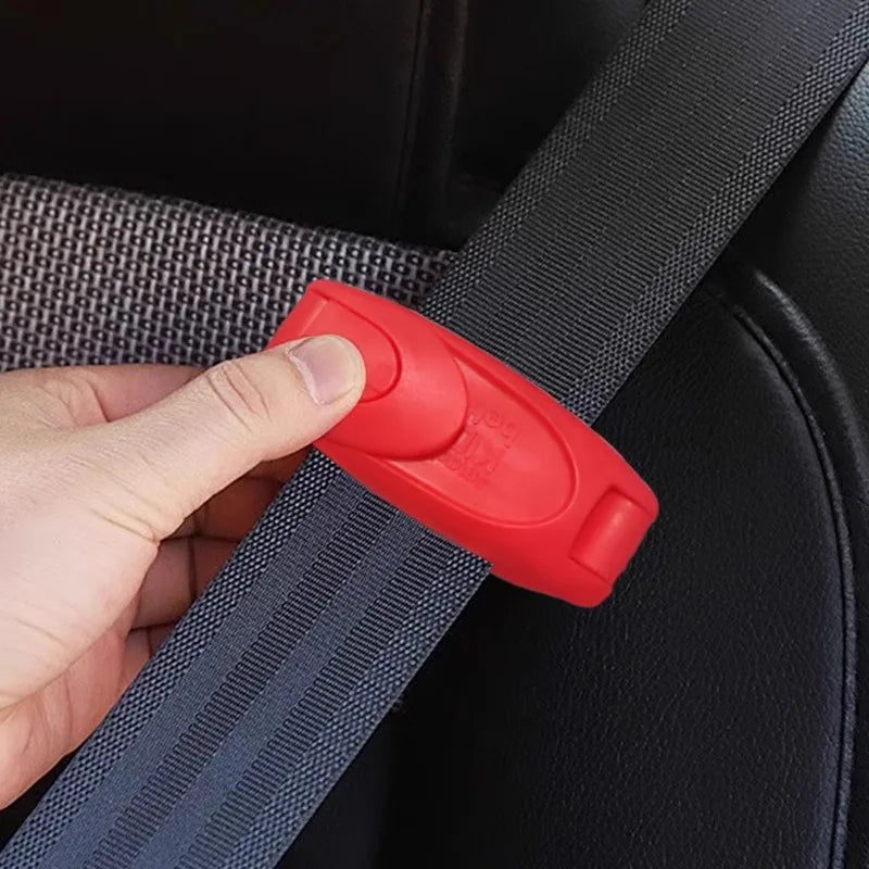 A hand is clipping a red seat belt strap onto a black car seat or surface.