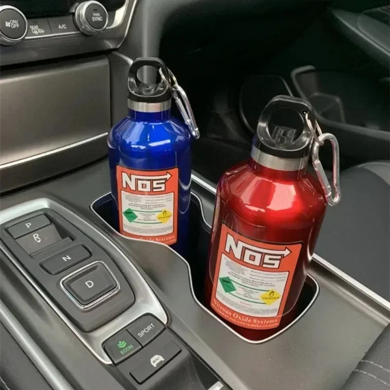 Two blue and red insulated stainless steel travel kettles are placed in a car console compartment.