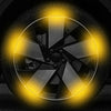 Gros plan sur une roue de voiture ou de moto avec un décal réfléchissant jaune brillant sur fond sombre.