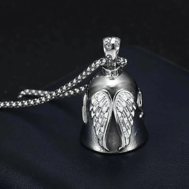 Silver angel guardian riding bell with detailed wings and a chain resting on a dark surface
