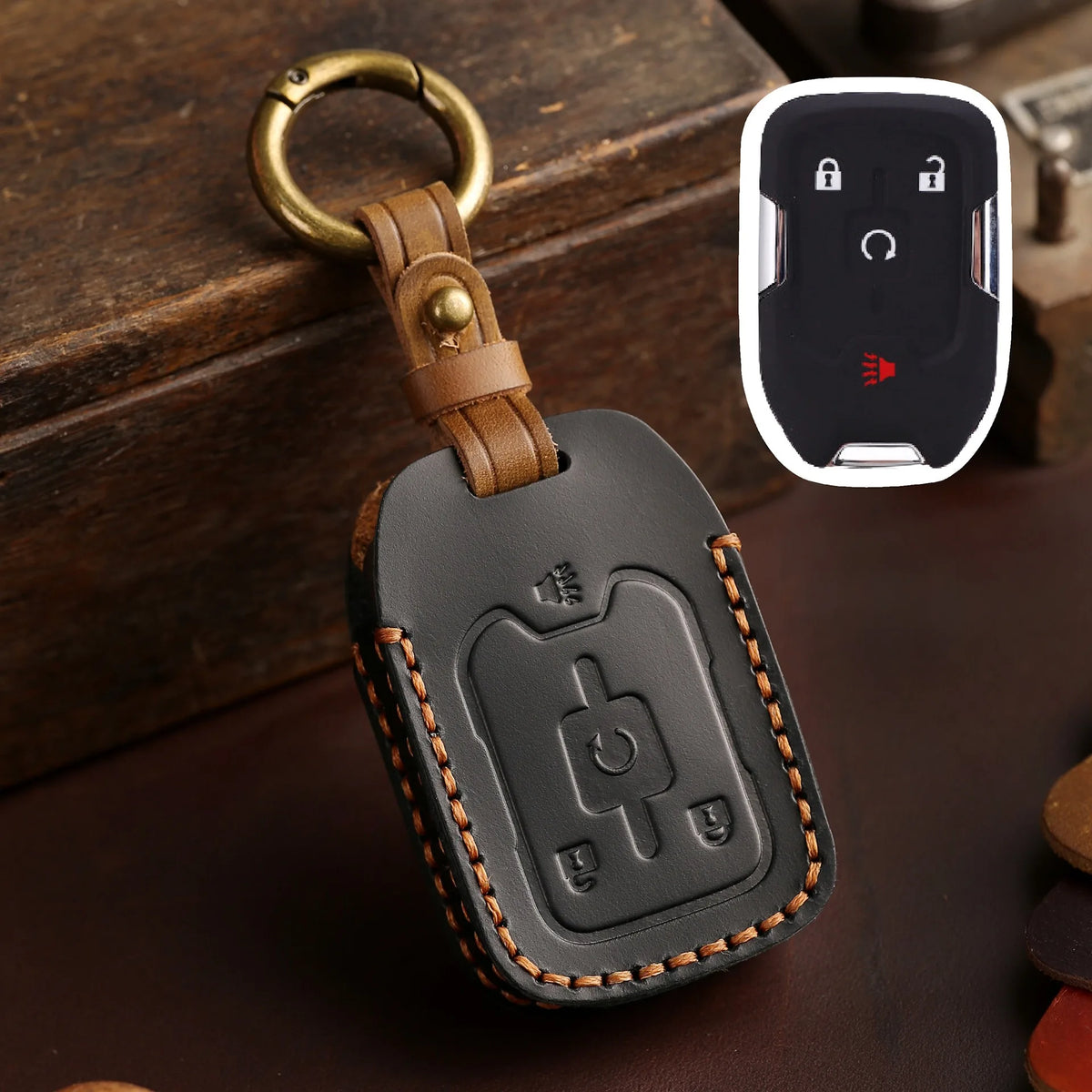 A black leather key cover with a metal ring and electronic fob is shown next to a white charging module.