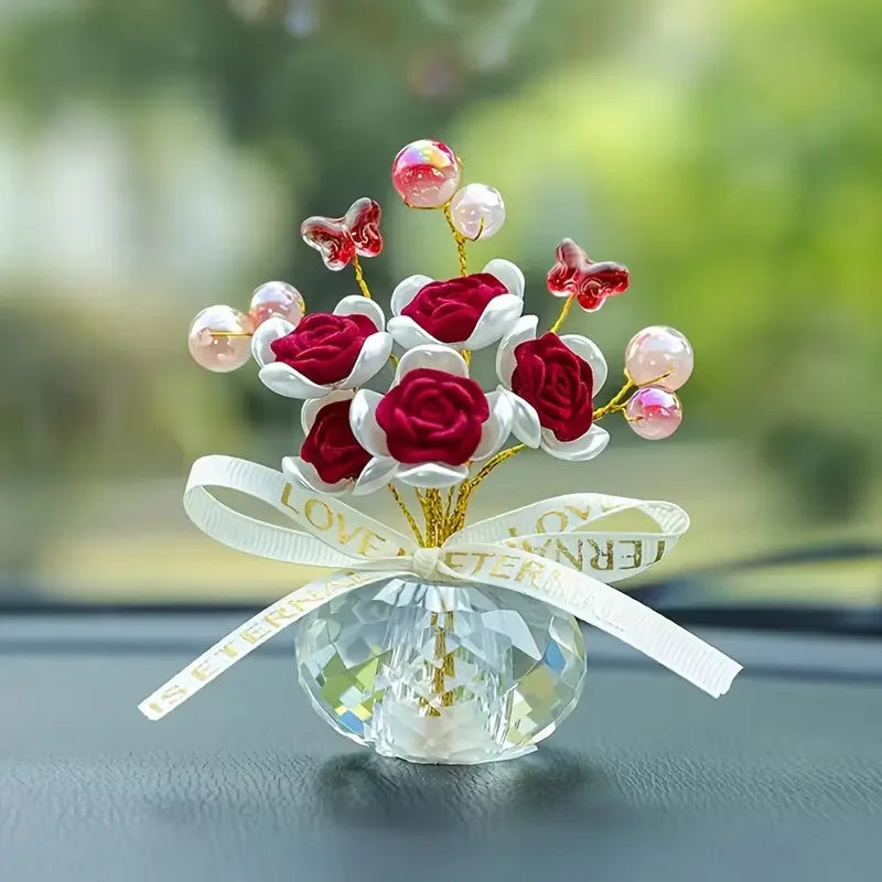 A crystal rose dashboard ornament featuring deep red and white roses with pink accents tied with a white ribbon.