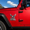 Primer plano de la puerta de una Jeep Wrangler roja con un emblema tridimensional de metal USA Faith Family Freedom.
