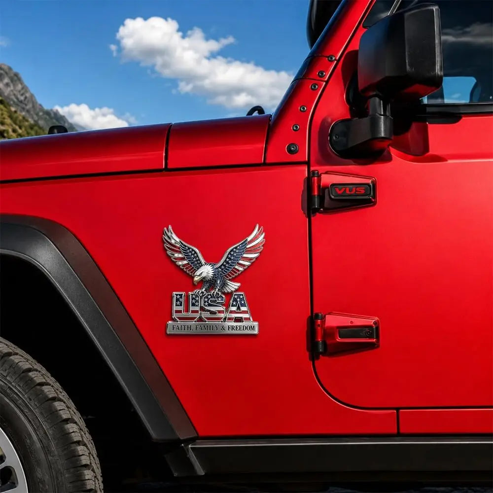 Primer plano de la puerta de una Jeep Wrangler roja con un emblema tridimensional de metal USA Faith Family Freedom.