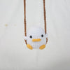 A white crocheted duck hanging from a brown string on a white background.