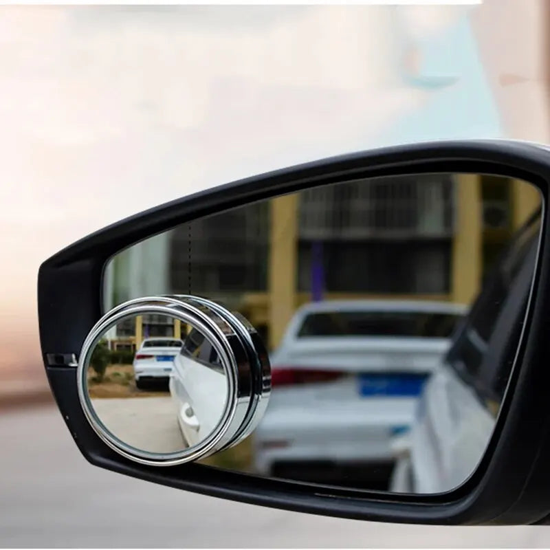 A close-up view of a black car mirror with a dual lens blind spot mirror attached.