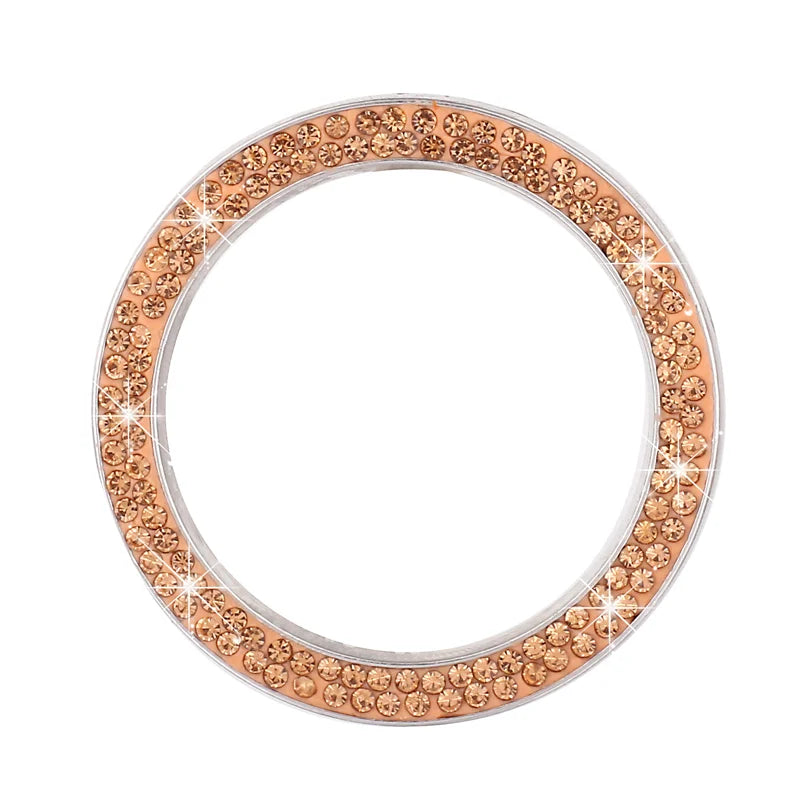 A circular cover for a car start button decorated with small rose gold diamond rhinestones.