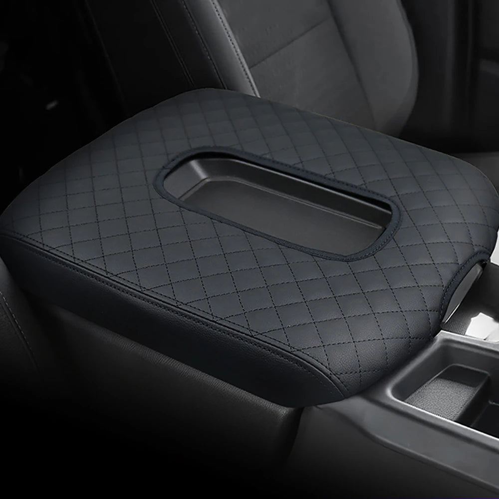 A black microfiber armrest pad with a rectangular cutout is shown in a vehicle interior.