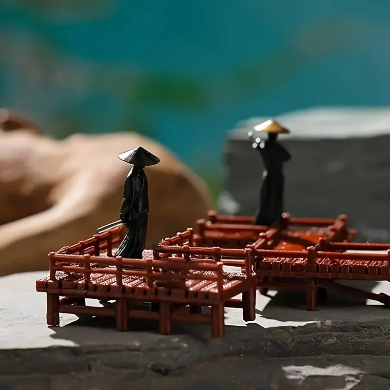 A set of miniature black samurai statues standing on a dark surface with a blurred green background.