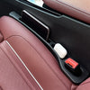 A close-up view of a car seat gap filler strip with a black and white design resting in a pink leather interior.