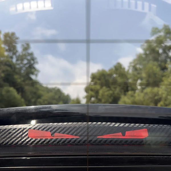 Primer plano de la ventana de un coche negro mostrando un vinilo con patrón de fibra de carbono roja en el revestimiento inte