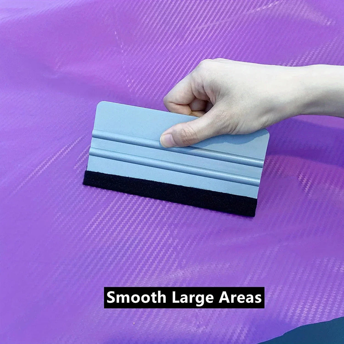 A hand applies a blue and black precision scratch-free decal applicator tool onto a purple surface.