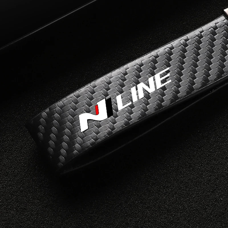 A close-up shot of a black carbon fiber style keychain with the N LINE logo on a dark background.