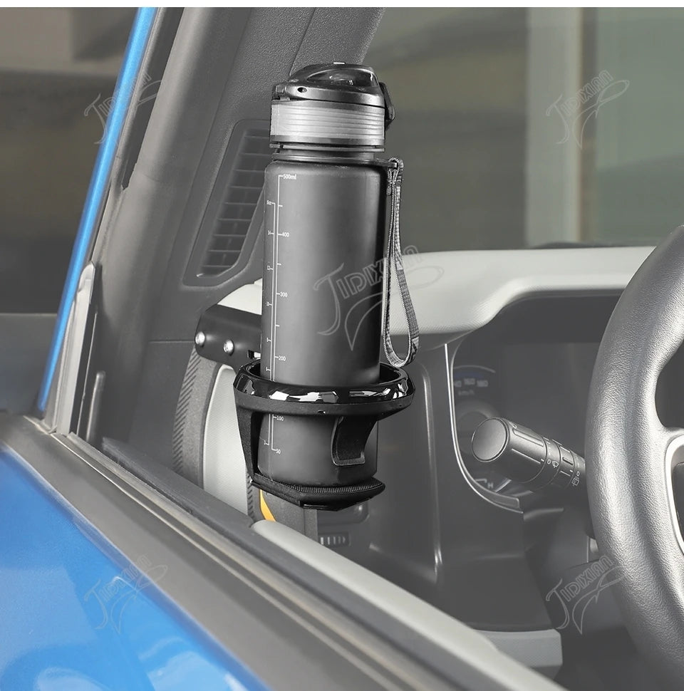 A close-up view of a black cup holder accessory mounted on the interior door panel of a vehicle.