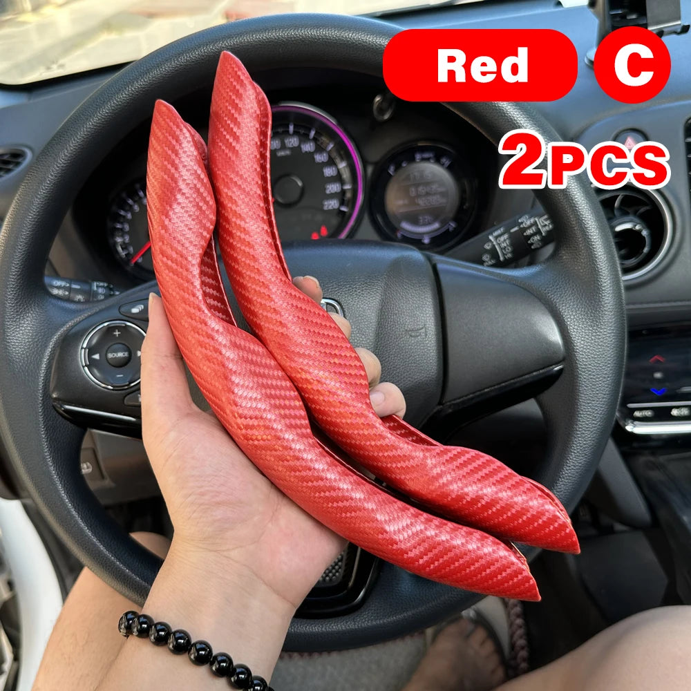 Two red carbon fiber steering wheel booster covers are shown being held in a hand inside a car interior.