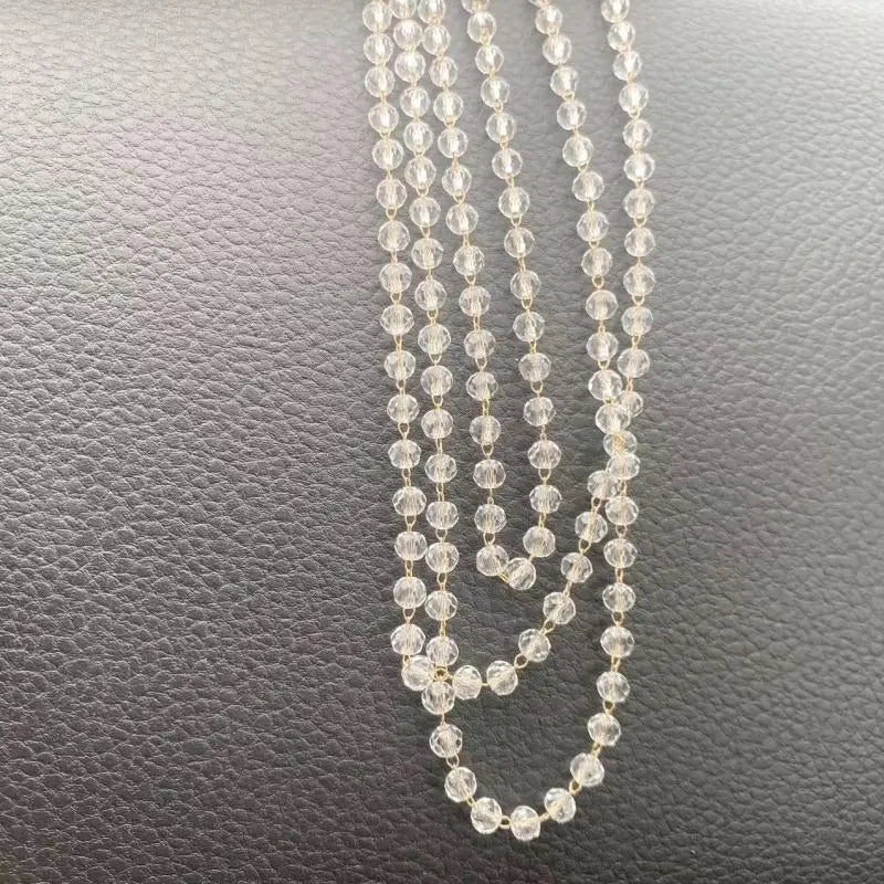 A delicate gold-toned chain necklace featuring small clear crystal beads and a pink lotus car pendant ornament.