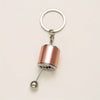 A rose gold metal keychain featuring a cylindrical charm and a circular keyring.