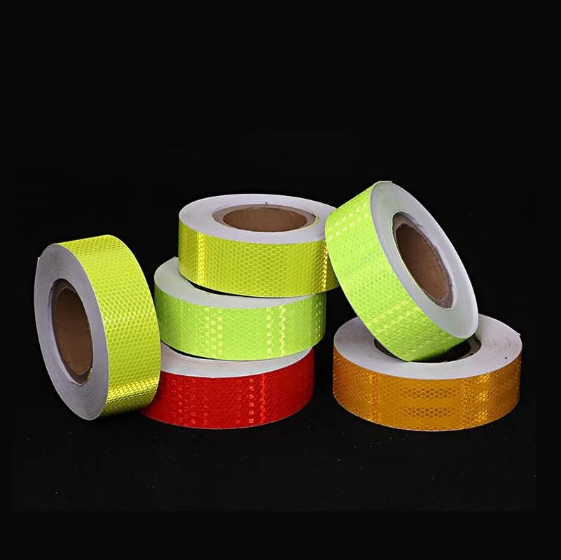 Rollos de cinta de advertencia de PVC reflectante en colores amarillo, verde lima y naranja.