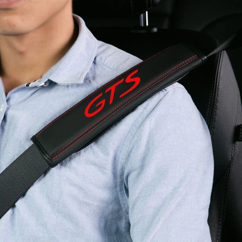 A person wearing a light blue shirt has a black seat belt protector cover with the letters GTS visible on it.