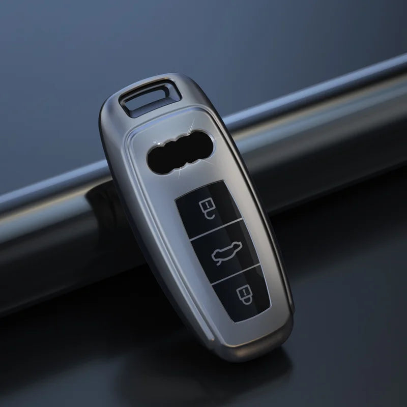 A silver leather car key case cover for an Audi, showing various key cutouts.