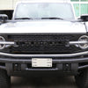 Gros plan sur la calandre et le pare-chocs avant noirs d'un Ford Bronco avec un cache de lettre blanche installé.