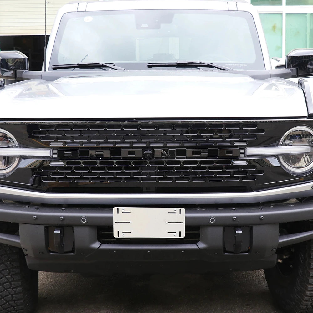 Gros plan sur la calandre et le pare-chocs avant noirs d'un Ford Bronco avec un cache de lettre blanche installé.