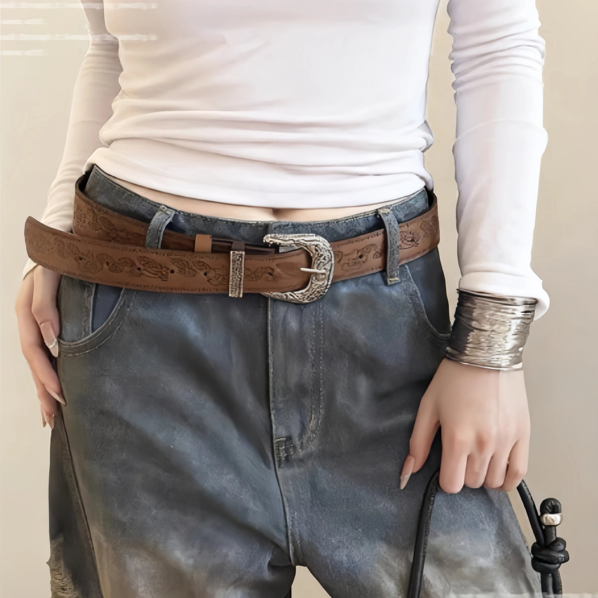 Nahaufnahme einer Frau mit einem retro braunen Gürtel über Jeans und ein weißes Oberteil.