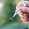 A hand is using a glass rod from an automotive windshield crack repair kit to apply sealant.