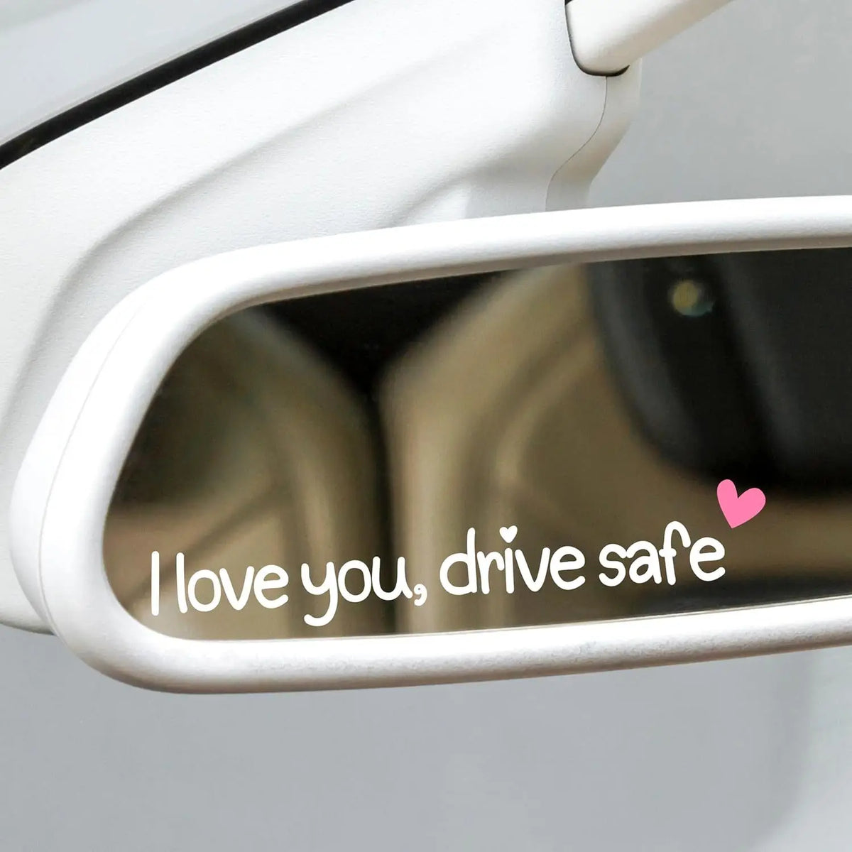 Gros plan sur le rétroviseur de voiture montrant un autocollant en vinyle cœur indiquant "I love you drive safe"