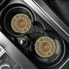 A close-up view of two brass gauge-marked silicone bullet car cup mats inside a vehicle console.