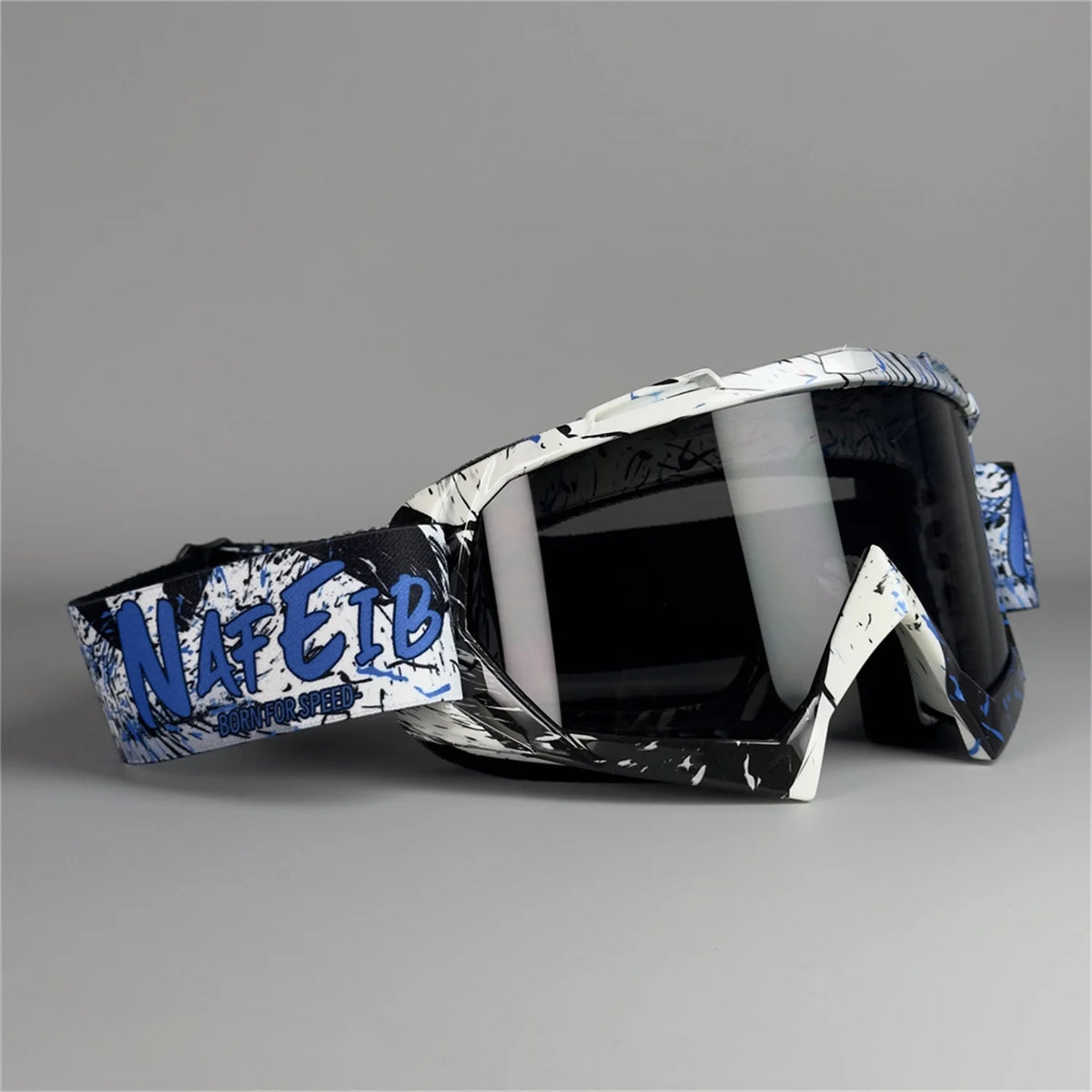 Un par de gafas de motocicleta negras con detalles gráficos blancos y azules sobre una superficie gris.
