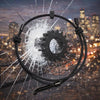 A black wristband with a gear-shaped device is shown shattering glass against a blurred city skyline.