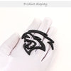 A black custom car body side emblem shaped like a snarling wolf head displayed on a white glove.